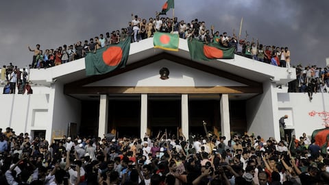 Manifestantes antigubernamentales exhiben la bandera nacional de Bangladesh mientras asaltan el palacio de la primera ministra, Sheikh Hasina, en Dhaka, el 5 de agosto de 2024 (Foto de K M ASAD / AFP)